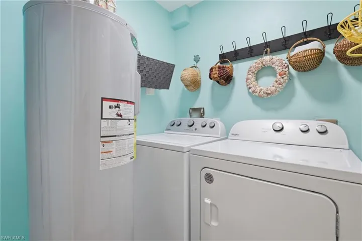 Dedicated laundry area featuring a white top-load washer, a white front-load dryer, and a wall-mounted coat rack