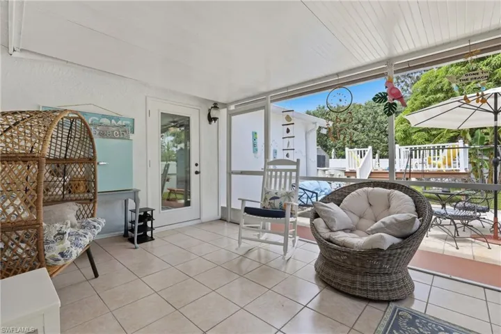 Screened lanai featuring neutral-toned tile flooring, direct outdoor access, a covered ceiling, and a clear view of the exterior deck