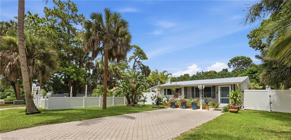 A light-colored residence framed by mature palm trees and lush greenery