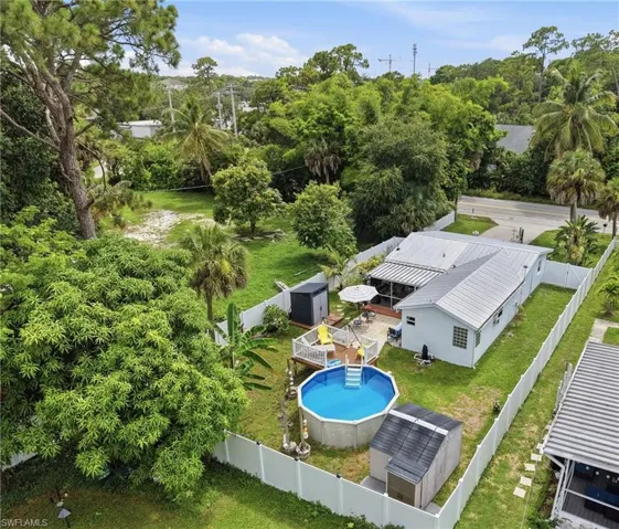 Fenced backyard featuring an above-ground pool, elevated wooden deck, and two storage sheds