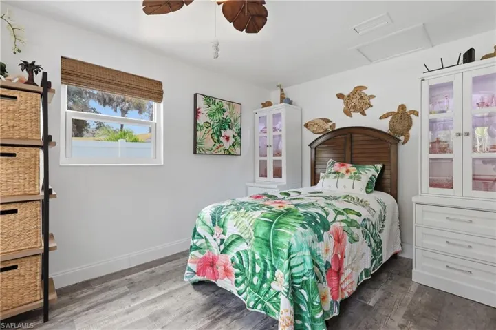 Bedroom featuring LVP flooring, a white trim baseboard, and a white framed window with a woven shade