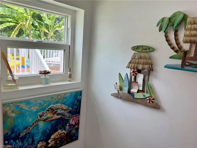 White framed window overlooking lush tropical foliage and a deck with white railings