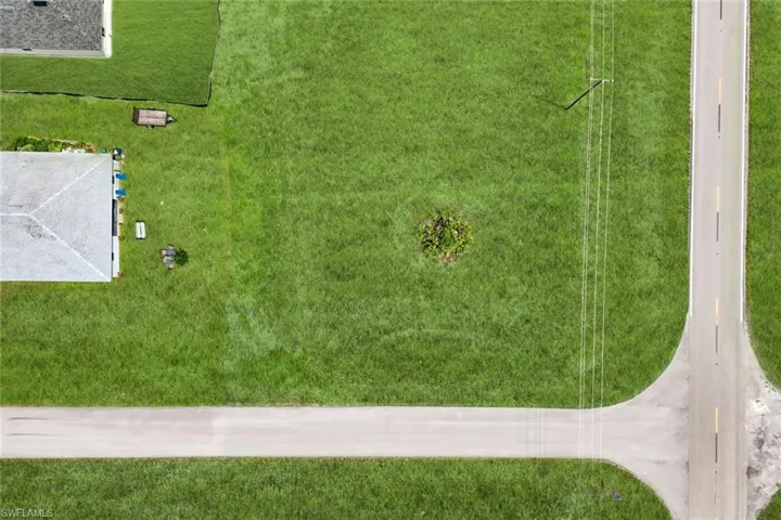 Expansive corner lot featuring a paved road and lush green space
