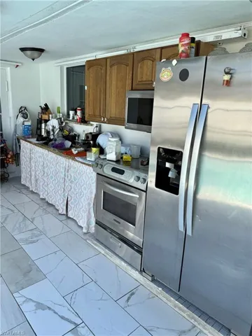 Kitchen with stainless steel appliances, light marble finish floors, and wood finish cabinets