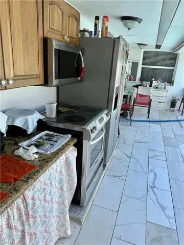 Kitchen with stainless steel appliances, light marble finish flooring, and wood finish cabinetry