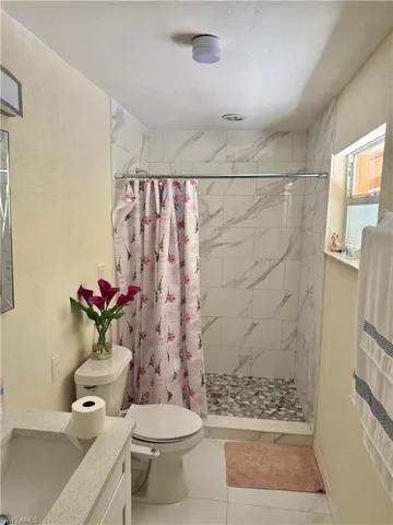 Full bathroom with a textured wall, vanity, a shower stall, a textured ceiling, and light tile patterned floors