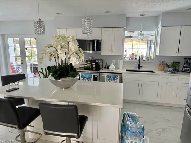 Kitchen with white cabinetry, light stone counters, and stainless steel appliances