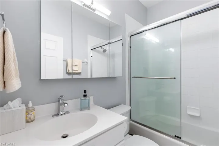 Full bathroom with combined bath / shower with glass door, vanity, and toilet