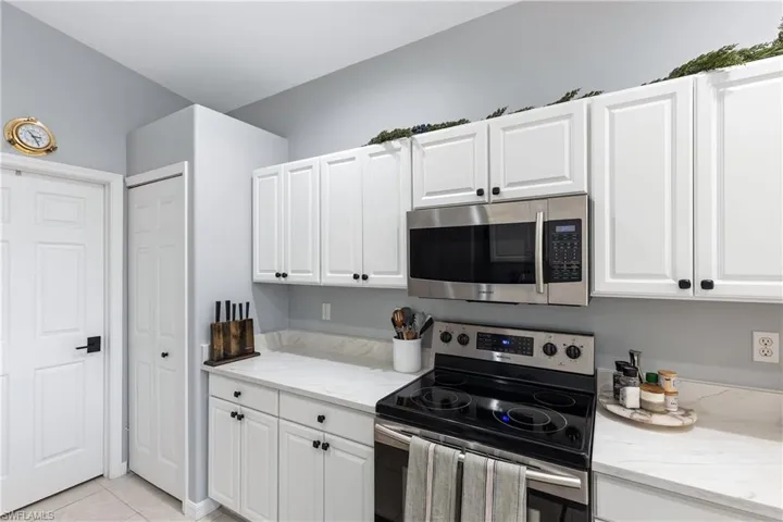 Kitchen featuring white cabinetry, stainless steel appliances, and light stone counters