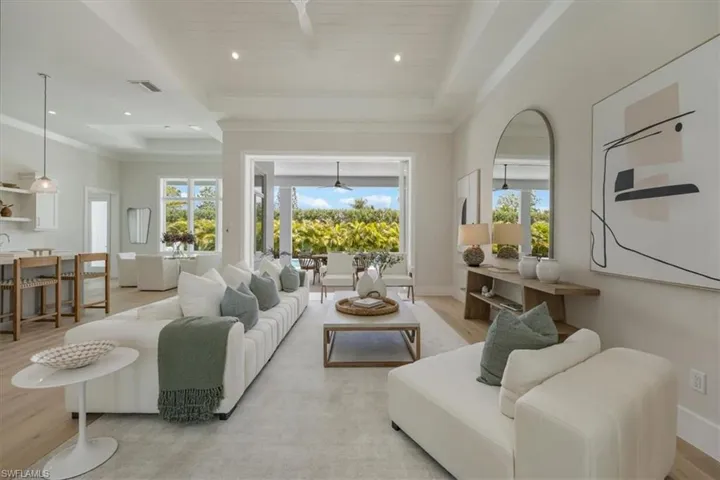 Main living area features include vaulted ceiling in the great room and 12'+ tray ceilings in kitchen, office, dining,  and primary. White oak flooring and 10' pocket impact sliders out to the shellstone paver pool deck create an open, airy feeling.