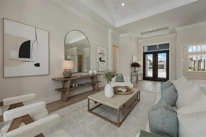 Main living area features include vaulted ceiling in the great room and 12'+ tray ceilings in kitchen, office, dining,  and primary. White oak flooring and 10' pocket impact sliders out to the shellstone paver pool deck create an open, airy feeling.