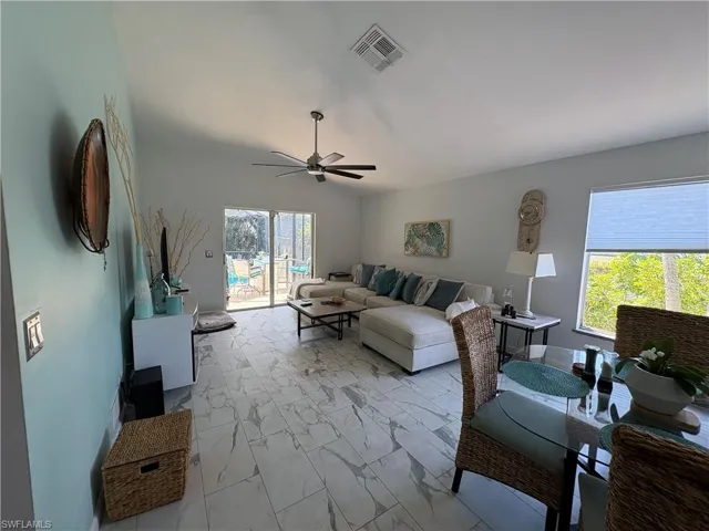 Living area featuring a ceiling fan and light marble finish flooring