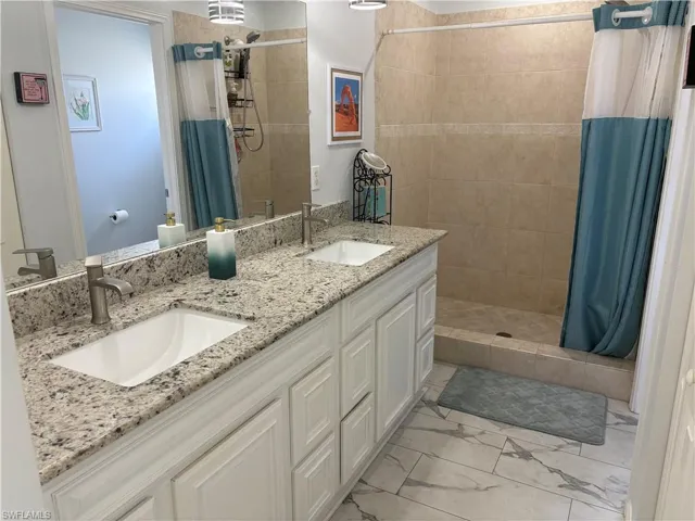 Bathroom featuring double vanity and a shower stall
