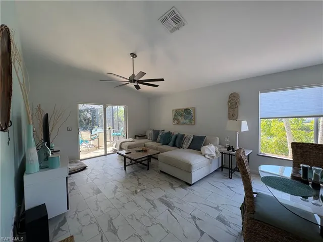 Living room with light marble finish flooring, lofted ceiling, and a ceiling fan