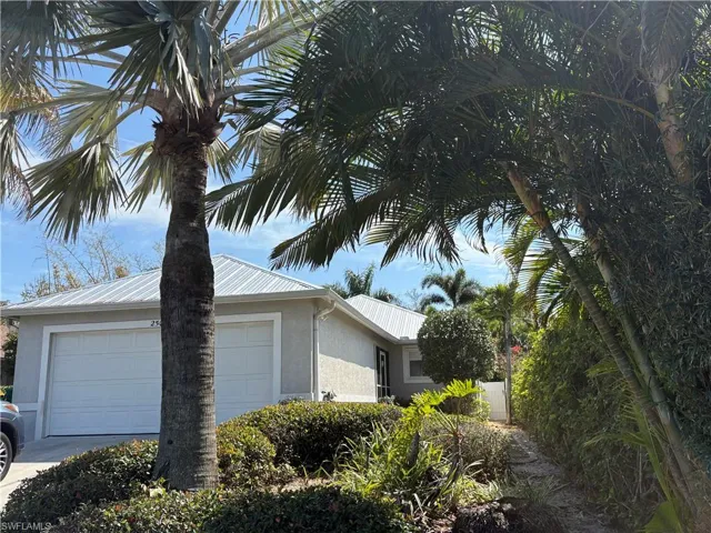 View of property exterior featuring stucco siding, a garage, driveway, and a metal roof