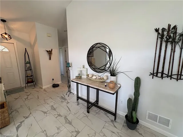 Foyer featuring light marble finish flooring and baseboards