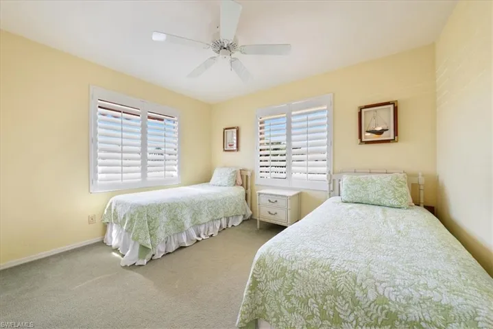 Bedroom with multiple windows, baseboards, ceiling fan, and carpet floors