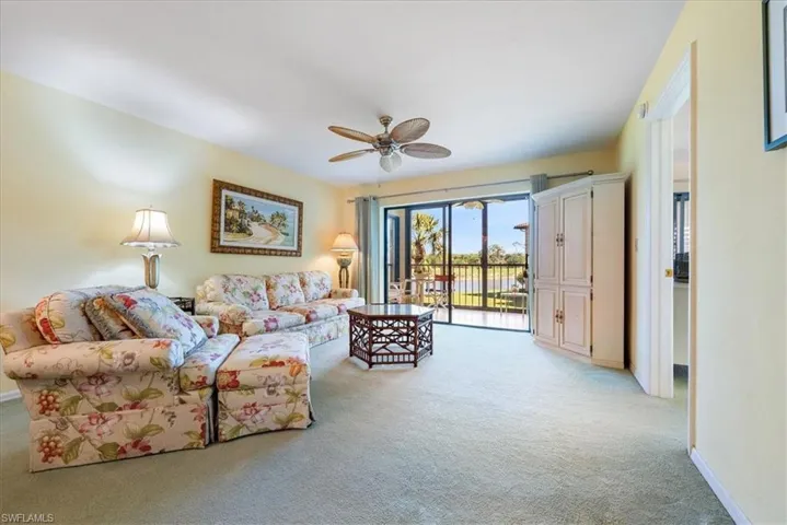 Living area featuring light carpet, baseboards, and ceiling fan