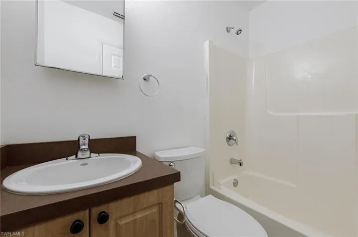 Full bathroom featuring vanity, washtub / shower combination, and toilet