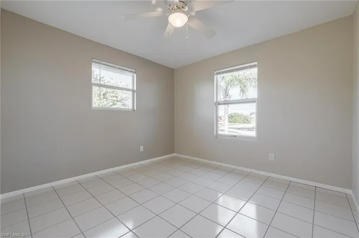 Spare room featuring light tile patterned flooring, ceiling fan, and plenty of natural light