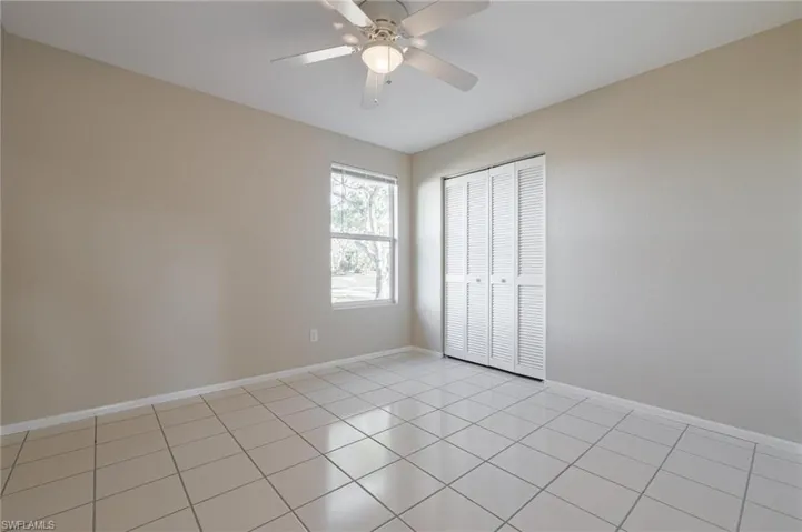 Unfurnished bedroom featuring a closet, light tile patterned floors, and ceiling fan
