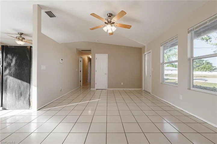Spare room with lofted ceiling, light tile patterned flooring, and ceiling fan