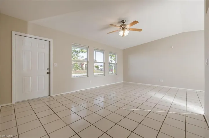 Tiled empty room with ceiling fan and vaulted ceiling