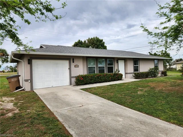 Ranch-style house with a garage and a front lawn