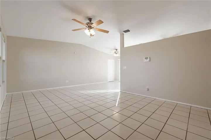 Unfurnished room featuring ceiling fan, vaulted ceiling, and light tile patterned floors