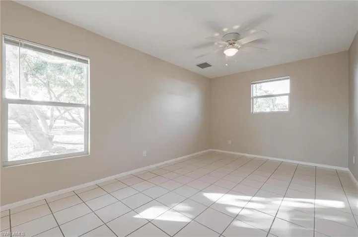 Empty room featuring light tile patterned flooring and ceiling fan
