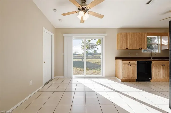 Kitchen featuring black dishwasher, light tile patterned floors, and plenty of natural light
