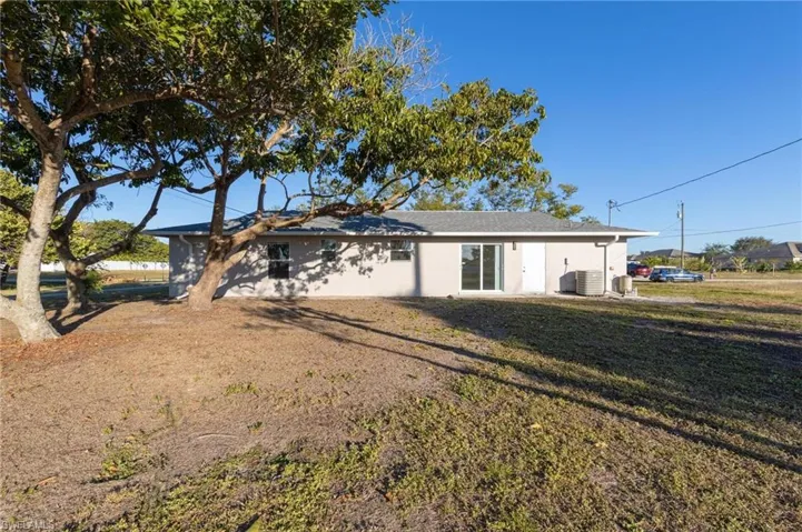 Rear view of house featuring a lawn and central AC unit