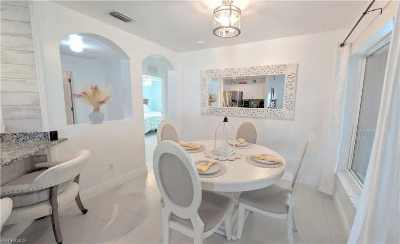 Newly painted Dining area featuring light-toned flooring, a window with natural light, and a decorative wall mirror