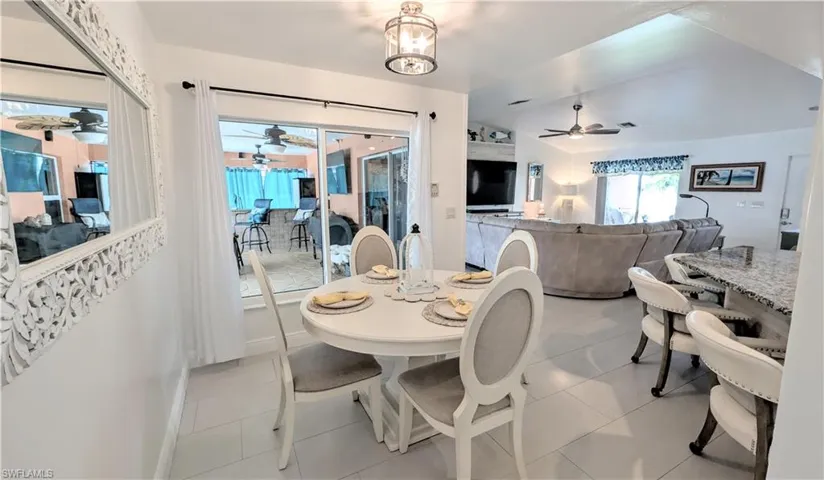 Open-concept interior featuring tile flooring, vaulted ceilings, and a large sliding glass door