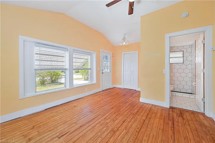 Spare room with light wood finished floors, baseboards, vaulted ceiling, and a ceiling fan
