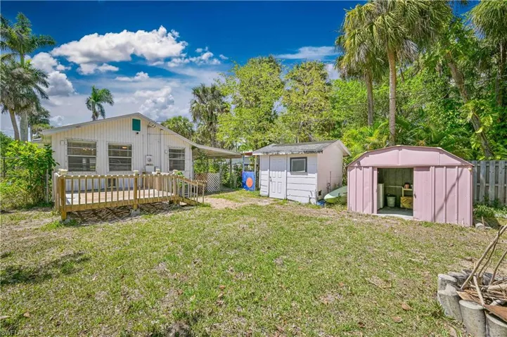 View of yard featuring an outdoor structure, fence, a deck, and a shed