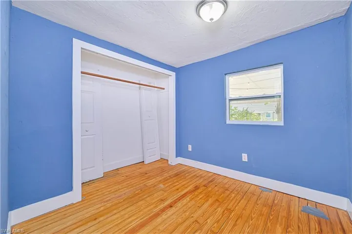 Unfurnished bedroom featuring a closet, baseboards, light wood finished floors, and a textured ceiling