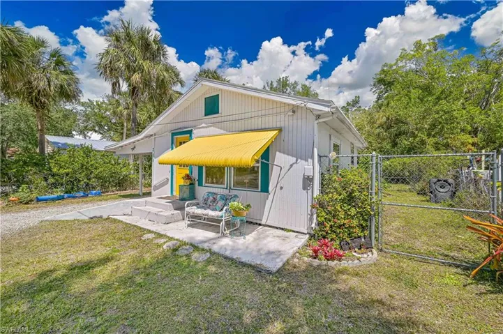 Rear view of property featuring fence, a gate, and a lawn