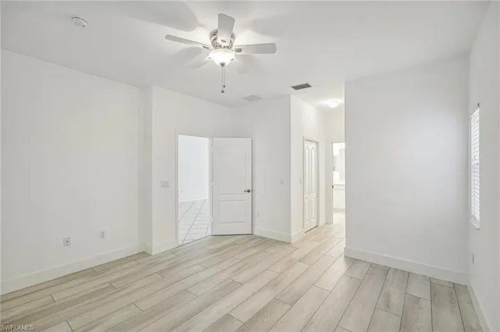Empty room featuring light wood-style flooring, a ceiling fan, baseboards, and a smoke detector