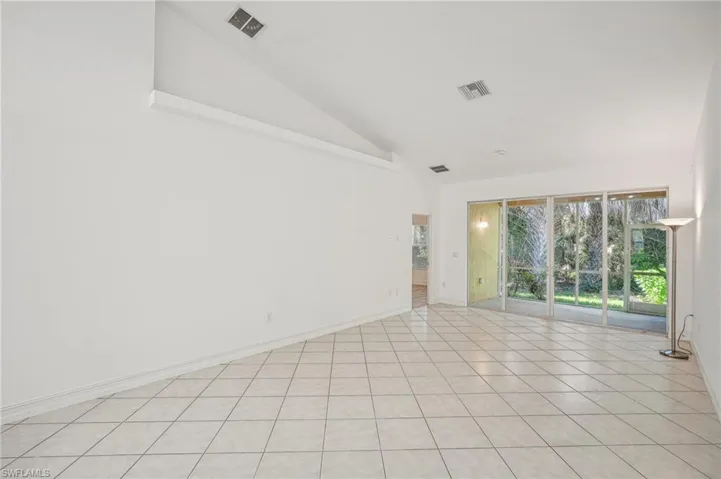 Spare room featuring high vaulted ceiling, baseboards, and light tile patterned floors