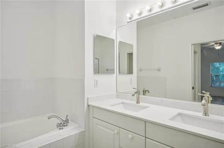 Full bathroom featuring double vanity and a garden tub