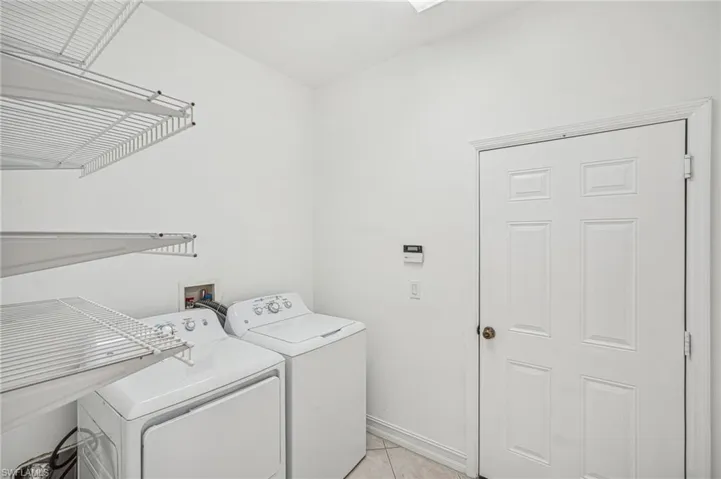 Washroom featuring washer and dryer, light tile patterned flooring, and baseboards