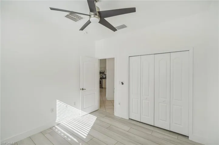 Unfurnished bedroom with light wood-style floors, a closet, baseboards, and a ceiling fan
