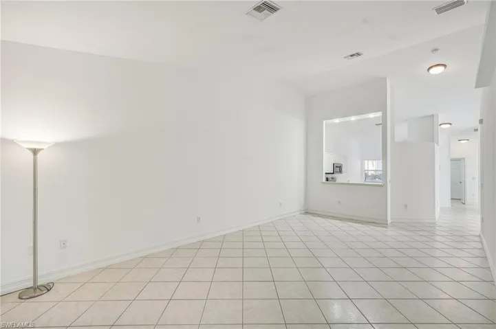 Spare room with light tile patterned flooring, lofted ceiling, and baseboards