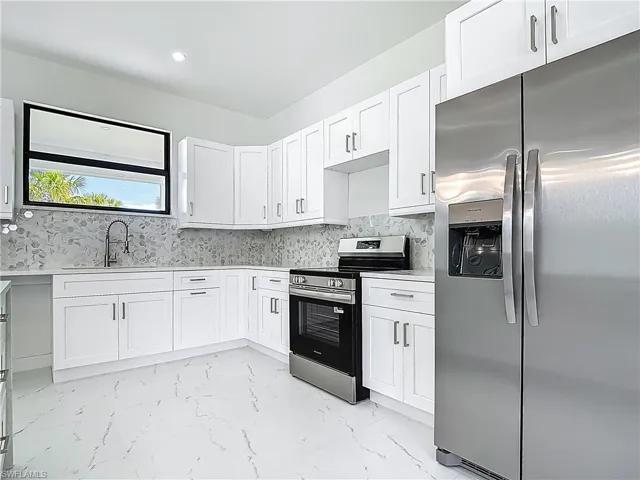 Kitchen with stainless steel appliances, light countertops, white cabinetry, light marble finish floors, and recessed lighting