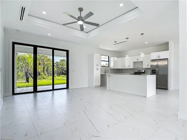 Kitchen featuring stainless steel fridge with ice dispenser, light marble finish floors, healthy amount of natural light, a tray ceiling, and recessed lighting
