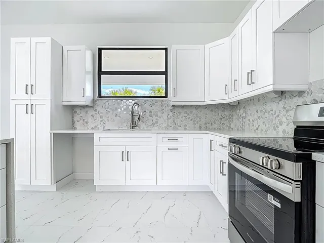 Kitchen with stainless steel range with electric cooktop, light marble finish floors, white cabinetry, and light countertops