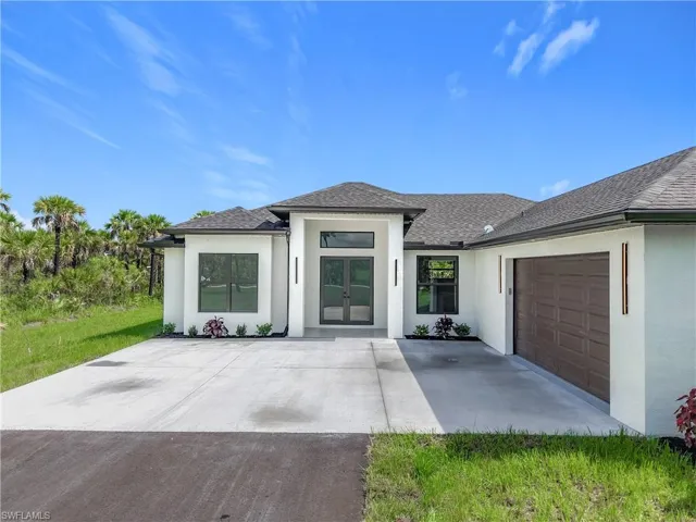 Prairie-style house featuring stucco siding, an attached garage, roof with shingles, french doors, and concrete driveway