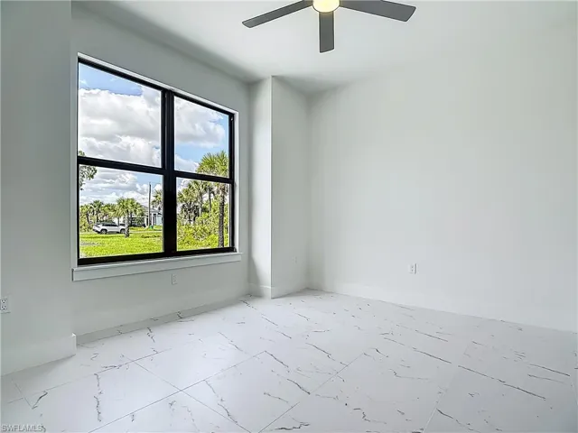 Unfurnished room with marble finish floors and ceiling fan