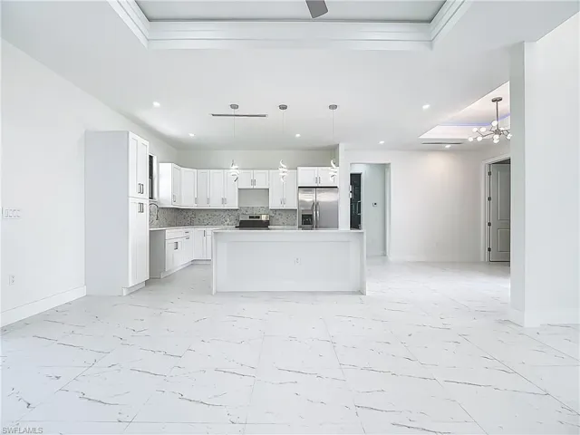 Kitchen with light marble finish floors, a raised ceiling, appliances with stainless steel finishes, open floor plan, and recessed lighting